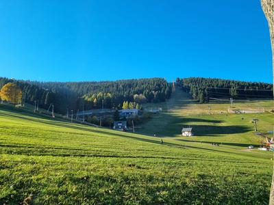 Grüne Bergwiese mit Sessellift unter klarem blauem Himmel an sonnigem Tag