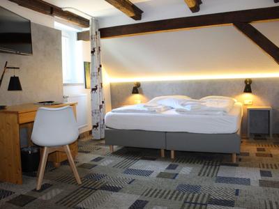 Modernes Hotelzimmer mit Doppelbett, Schreibtisch und Stuhl, beleuchtet durch warmes LED-Licht