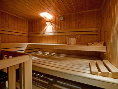 Gemütliche Sauna mit Holzbänken und einem Korb zur Entspannung.