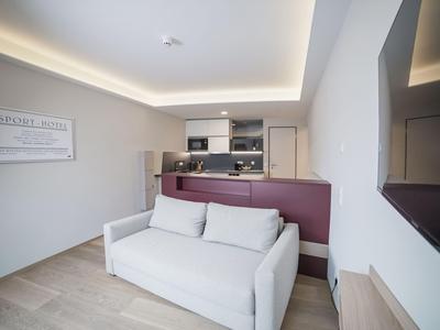 Modern eingerichtetes Wohn- und Küchenbereich mit weißem Sofa und eingebauter Küchenzeile.