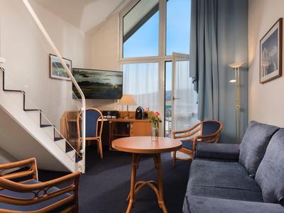 Cozy hotel lounge area with sofa, armchairs, table, and large window with a view.