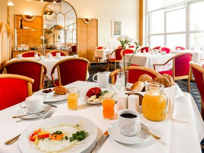 Breakfast table with various dishes and drinks in a bright, cozy restaurant.