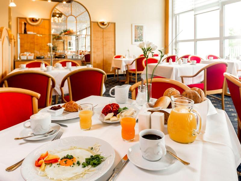 Breakfast table with various dishes and drinks in a bright, cozy restaurant.