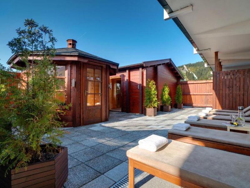 Rooftop terrace with loungers, towels, and wooden cabins under clear sky.