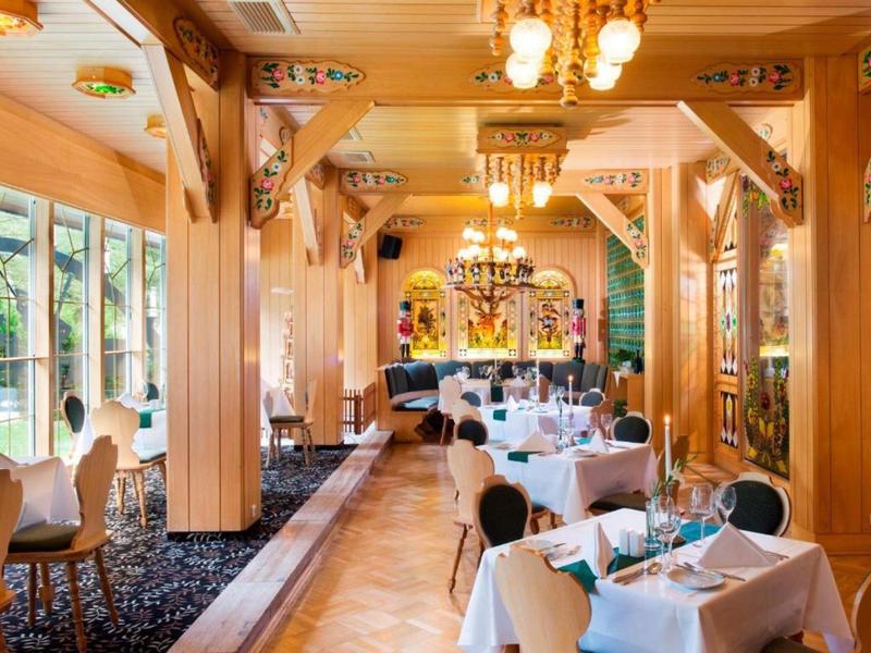 Elegant restaurant with wooden ceiling beams and tables set with white tablecloths.