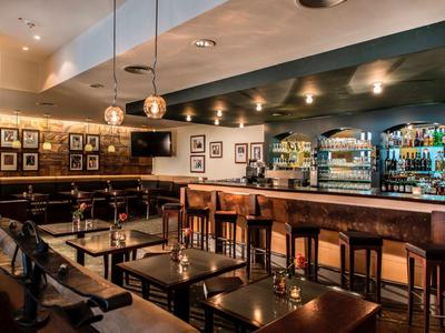 Moderne hotelbar met houten counter, krukken en gezellige zitgedeelten bij gedimd licht.