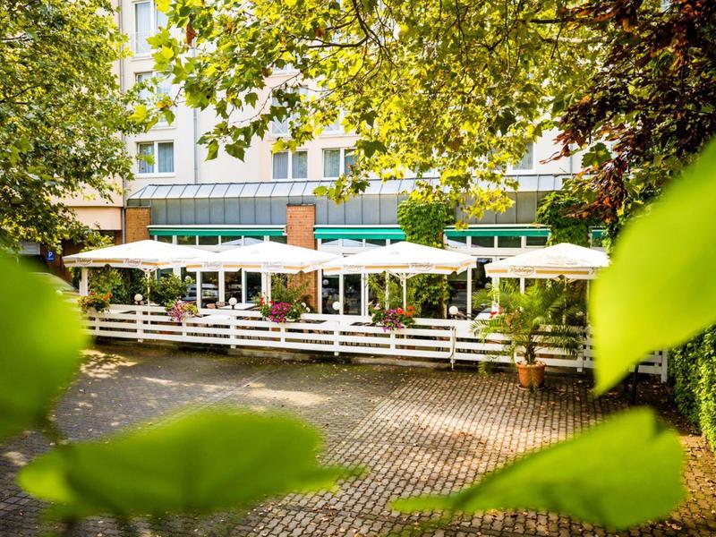 Außenrestaurantbereich eines Hotels mit Sonnenschirmen und grüner Umgebung