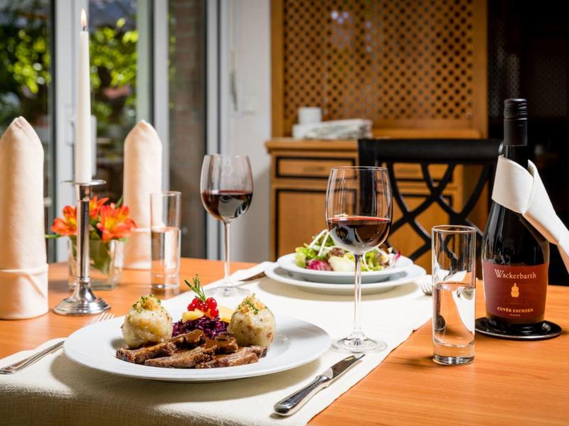 Elegantes gedecktes Restauranttisch mit Gourmetgericht, Wein und Blick ins Grüne.