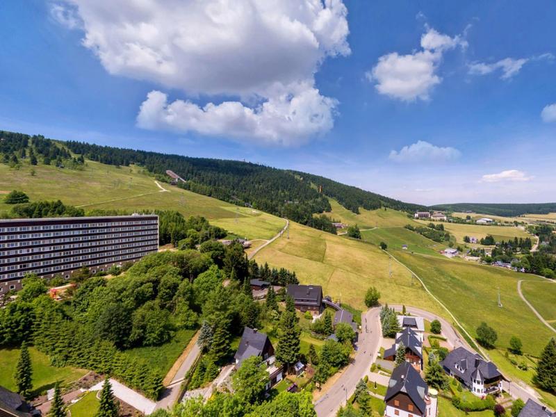 Mountain hotel with vast meadows and a valley view under a blue sky with clouds