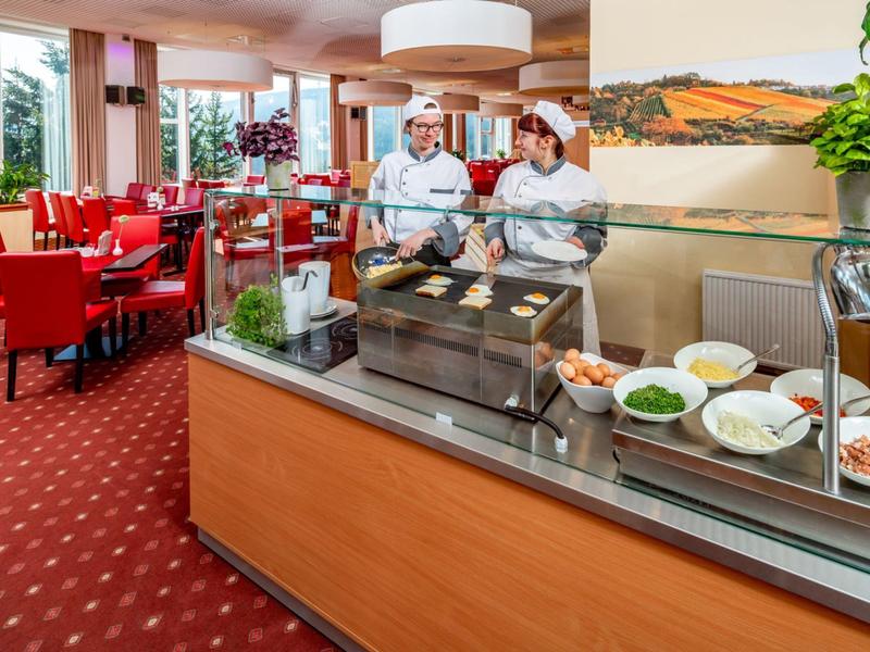 A hotel buffet with fresh ingredients and two chefs in the background in an elegantly furnished dining room.