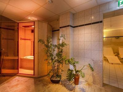 Salle avec sauna, plantes et chaises longues, éclairage chaleureux