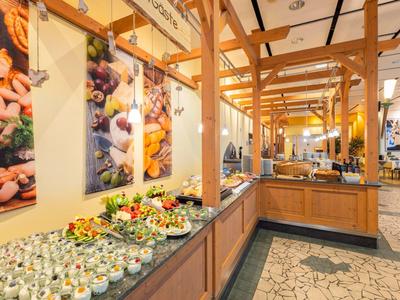 Buffet avec divers plats et poutres en bois au plafond dans une salle à manger lumineuse.