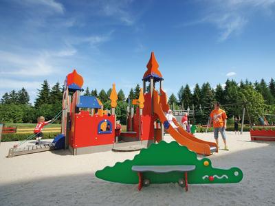 Kleurrijke speeltuin voor kinderen met glijbanen en klimrekken op een zonnige dag.