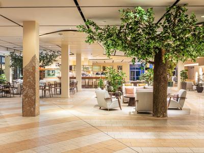 Interior moderno de hotel con grandes árboles y áreas de descanso acogedoras.