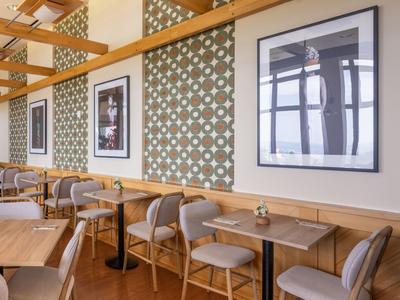 Área de comedor moderna con sillas de madera, mesas y cuadros decorativos en la pared.