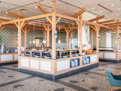 Área moderna de desayuno con estaciones de buffet y marcos de madera en un hotel.