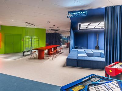 Área lounge moderna con nichos para sentarse, mesa de ping pong y futbolín colorido.