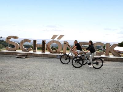Dos personas montando bicicletas frente a letras grandes que dicen 'Schönau am Königssee'.
