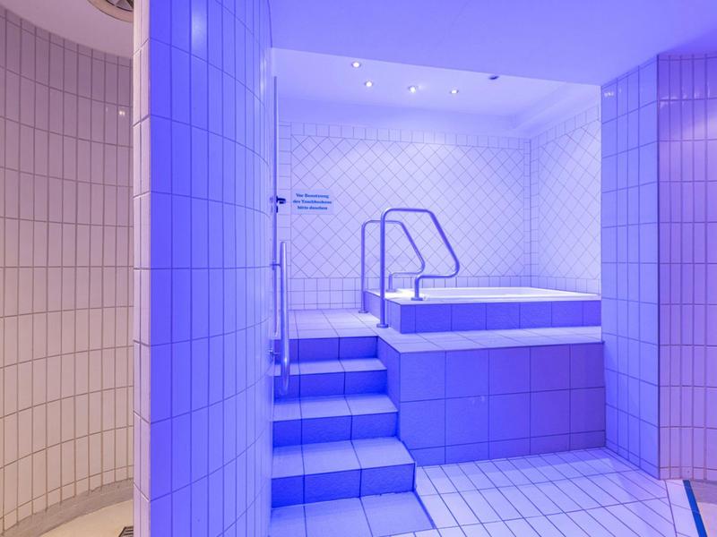 Espace bien-être moderne avec piscine chauffée et escalier dans des tons bleus froids.