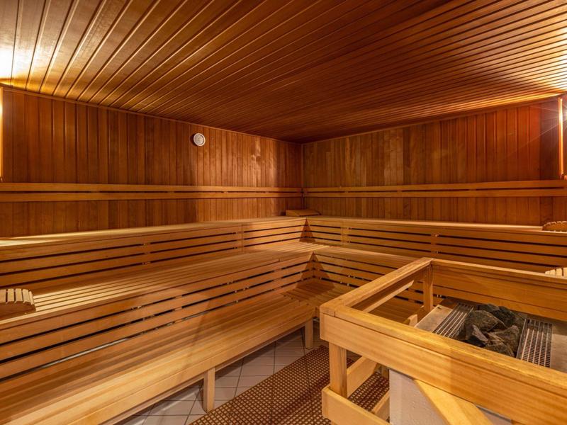 Sauna traditionnelle avec panneaux en bois et bancs en bois en forme de L.