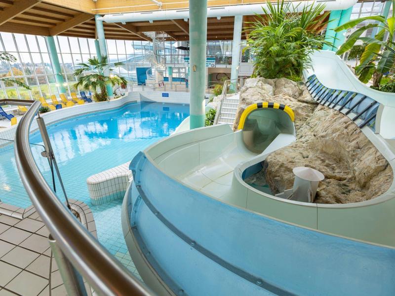 Vue intérieure d'une piscine moderne avec toboggan et plantes