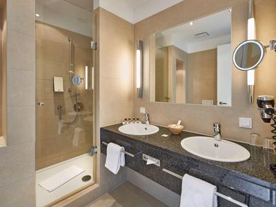 Modernes Hotelbadezimmer mit Doppelwaschbecken, großer Spiegel und Duschkabine.