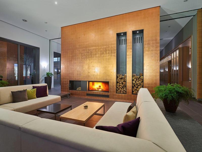 Moderner Hotel-Lounge-Bereich mit großem Kamin, Sofa und eleganter Holzakzentwand.