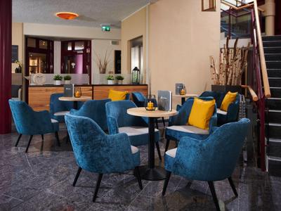 Gemütliche Sitzecke mit blauen Sesseln und kleinen Tischen in einem stilvollen Hotelbereich.