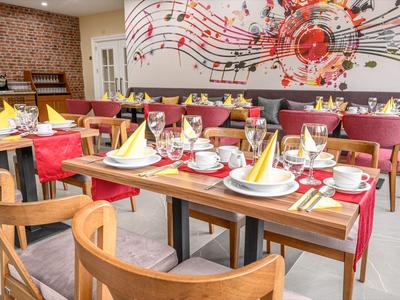 Elegantní restaurace s barevně prostřenými stoly a nástěnným uměním not.