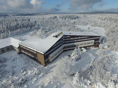 A large modern hotel surrounded by snow-covered trees and a winter landscape.