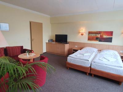Bright hotel room with double bed, sofa, and large window.