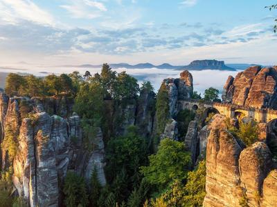Rock formation with bridge and trees at sunrise in a vacation area.