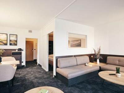 Helles Hotelzimmer mit modernen Sofas, Tischen und minimalistischer Dekoration.