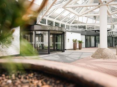 Voorplein van een hotel met glazen dak en entree met planten