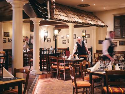 Gezellig restaurant met houten stoelen, witte zuilen en formeel geklede obers.