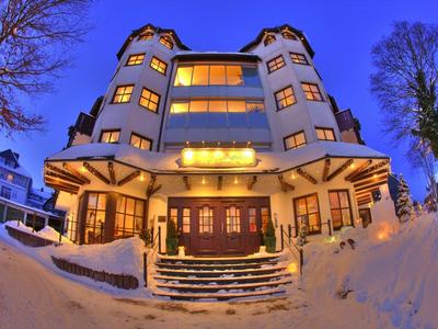 Hotel mit vier runden Türmen, beleuchtet bei Schnee und Abenddämmerung
