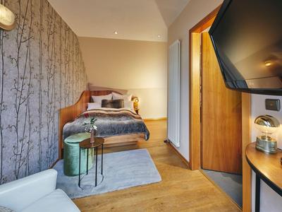 Gemütliches Hotelzimmer mit Einzelbett, modernem Dekor und Fernseher an der Wand.