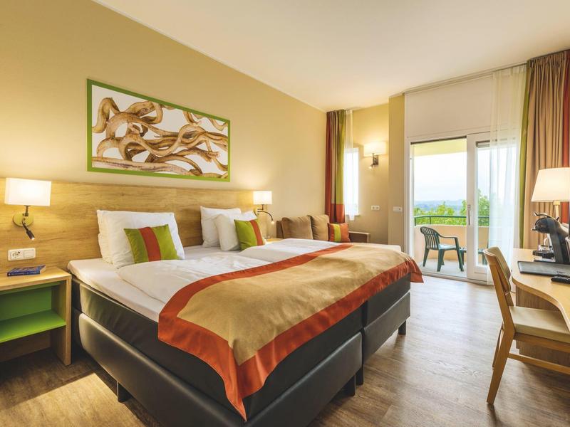 Gemütliches Hotelzimmer mit Doppelbett, Holzmöbeln und Balkon mit Aussicht bei Tageslicht.