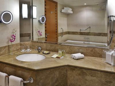 Luxuriöses Badezimmer mit Marmorwaschtisch, Spiegeln, Handtüchern und Badewanne im Hintergrund.