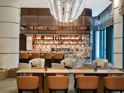 Modern eingerichtete Hotelbar mit Holz- und Beerelementen sowie eleganter Beleuchtung.