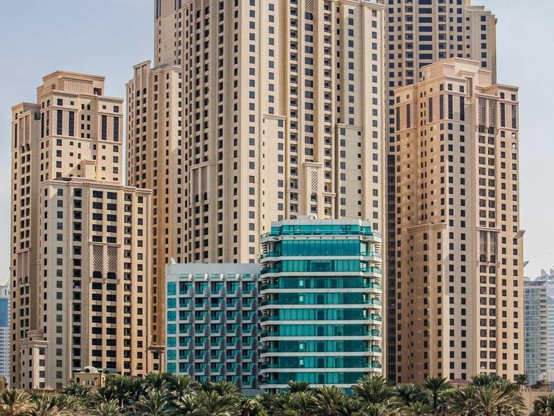 Hohe moderne Wolkenkratzer mit vielen Fenstern am Strand unter blauem Himmel.
