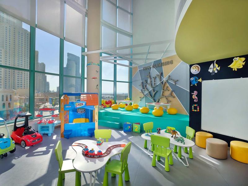 Heller, moderner Spielraum mit kindgerechten Möbeln, bunten Spielzeugen und großem Fenster.