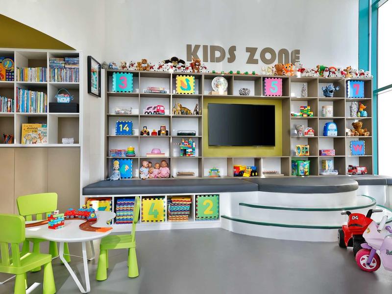 Kinderbereich mit bunten Möbeln, Spielzeug, Büchern und TV in heller, freundlicher Umgebung.