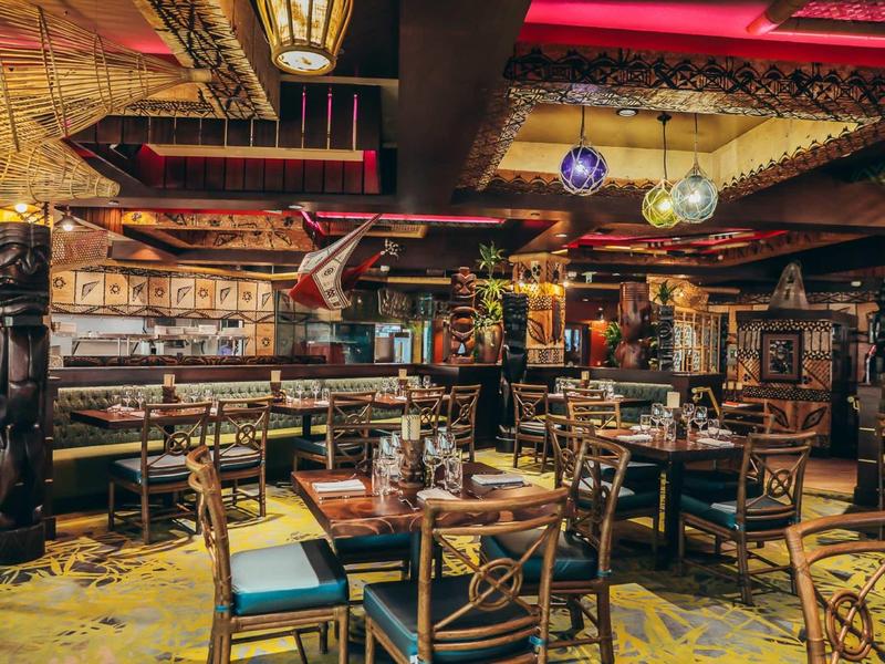 Gemütliches Restaurant mit Holzmöbeln, Teppichboden und warmem, gedämpftem Licht.