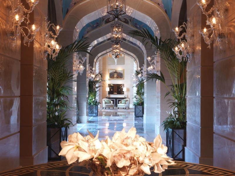 Prächtiger Gang mit Kronleuchtern, Blumenarrangement und blau bemaltem Gewölbe.