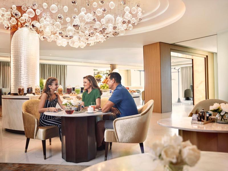 Drei Personen sitzen an einem runden Tisch in einem modern eingerichteten, hellen Raum.