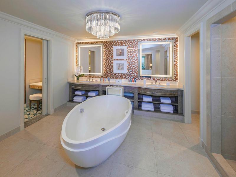 Luxuriöses Badezimmer mit freistehender Badewanne, hellen Fliesen und großem Doppelwaschbecken.