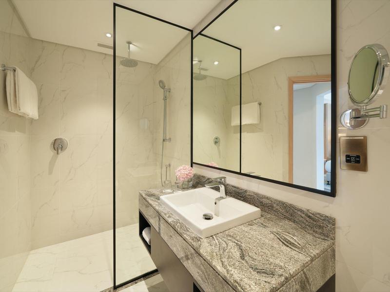 Moderne Badezimmer mit Glasduschwand, großem Spiegel und grauer Marmorplatte mit integriertem Waschbecken.