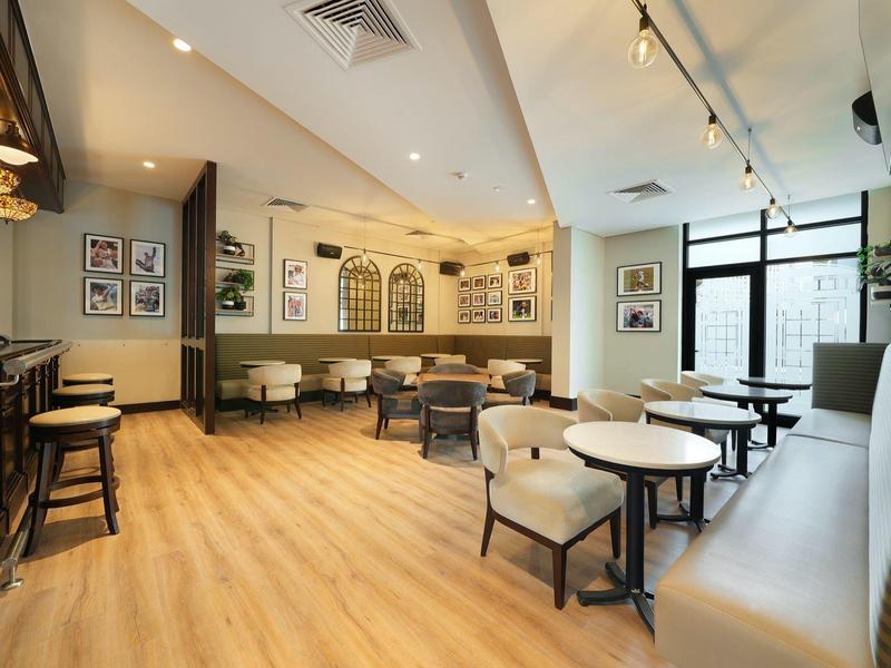 Helles Café mit Holzboden, weißen Wänden, rundem Mobiliar und großen Fenstern für Tageslicht.