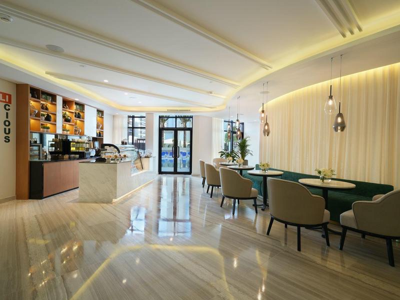 Moderner Gastraum mit hellem Marmorboden, stilvollen Sesseln, Tischen und elegantem Tresenbereich.